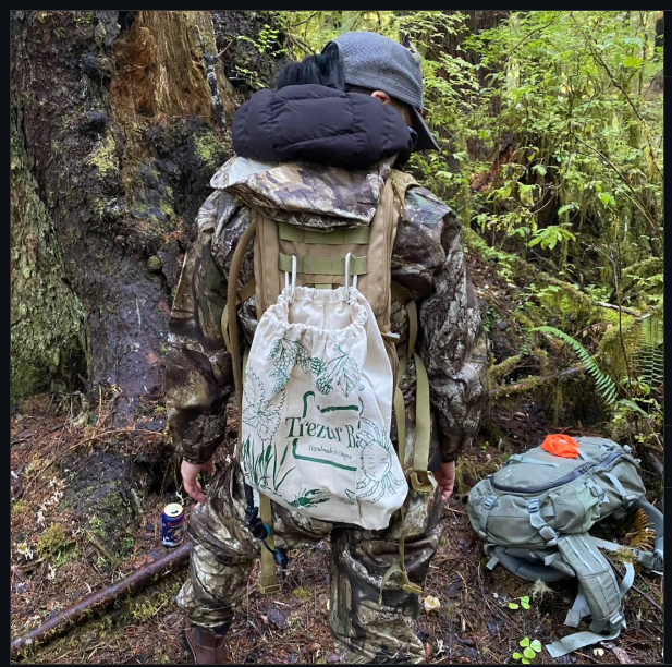 Foraging Bag attached to a backpack while being used in the woods